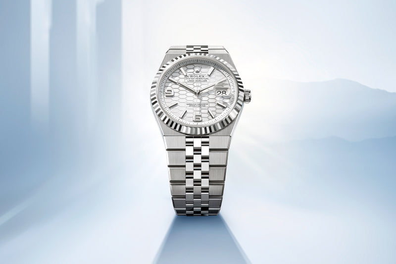 A silver Rolex watch with a patterned dial is displayed against a light blue, abstract background.