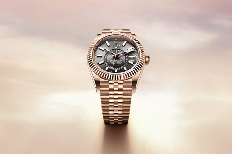A gold Rolex watch with a dark face and metal bracelet displayed on a soft, light background.