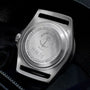Close-up of a silver watch case with 'Tudor Geneve' branding on a dark background