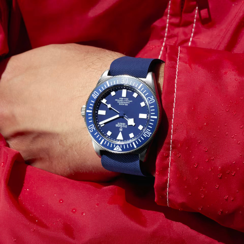 Blue watch with a blue strap on a wrist wearing a red jacket