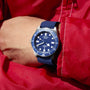 Blue watch with a blue strap on a wrist wearing a red jacket