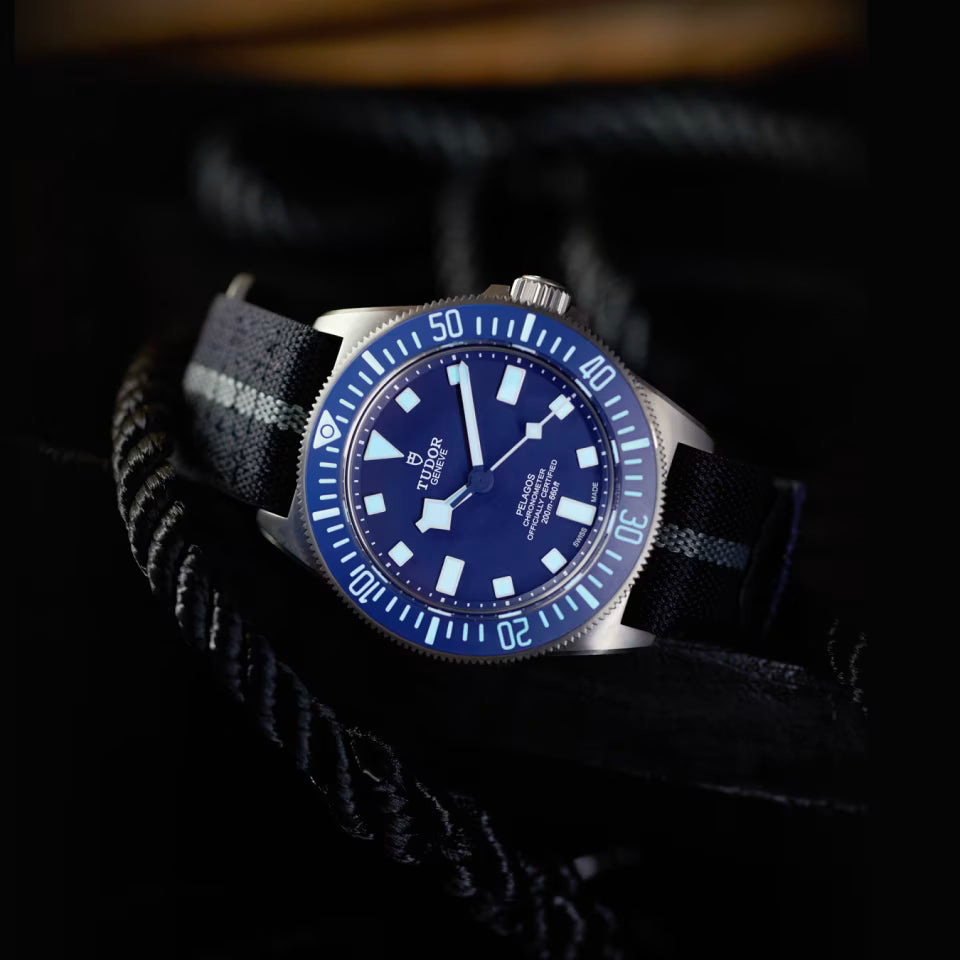 Watch with a blue dial and black strap on a dark background