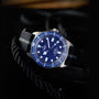 Watch with a blue dial and black strap on a dark background