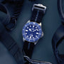 Watch with blue dial and black strap on a dark background