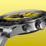 Black and yellow chronograph watch with black bezel, stainless steel case, and metal bracelet against yellow background.