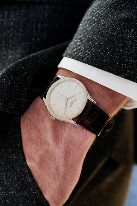 Close-up of a wrist wearing a watch with a dark strap and light face.