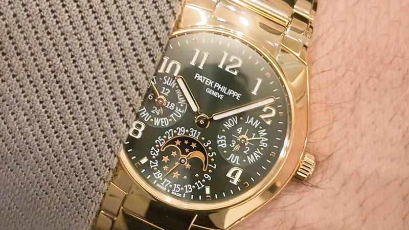 A gold Patek Philippe wristwatch with multiple dials is worn on a person’s wrist in close-up view.